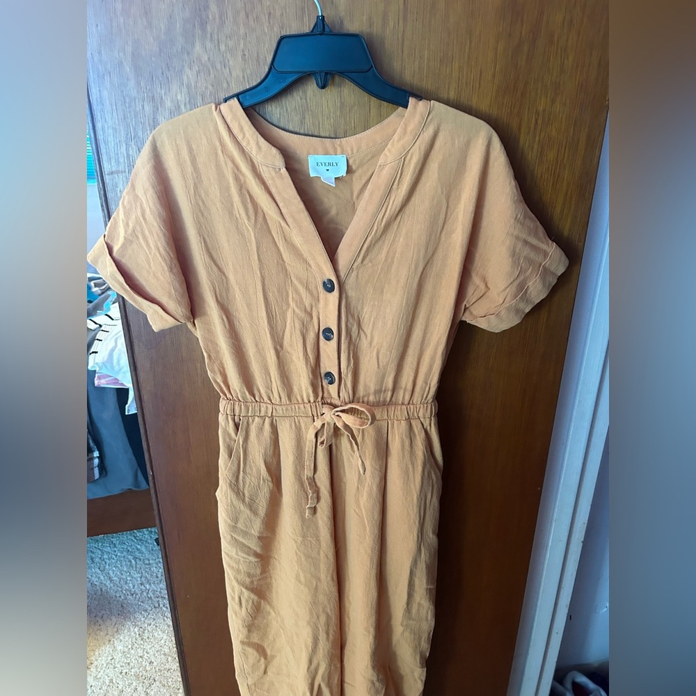 Yellow jumpsuit, brown buttons and has a cute bow